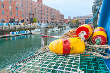 Yellow and red striped buoys or floats on crab pots against background of fishing port and...
