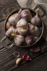 Garlic in a dish on an old wooden table. Vintage, rustic style.
