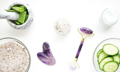 Face rollers, gouache massager scraper, made of natural amethyst. Self-care kit. home Spa products on a white backgroun. Face masks with cucumber and aloe.