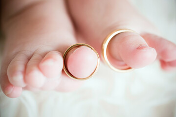 Detalle de anillos de una pareja recién casada colocados en los dedos de unos pies de bebé...
