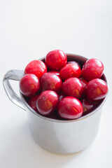 Sweet cherries in a steel mug on a white paper background