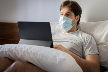 Man working in bed, doing home office because he is sick.