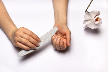A woman files her nails with a file. Giving nails a square shape. Manicure at home.