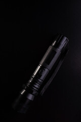 Black tactical flashlight on a black background