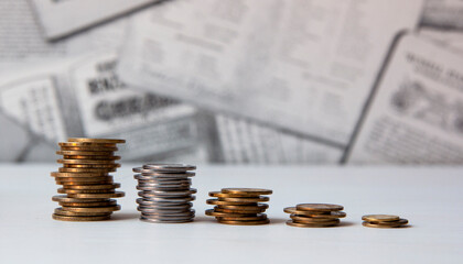 Coins are folded in a column on a newspaper background