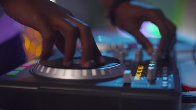  Close up of hands of unrecognizable DJ using controller and mixing music at party