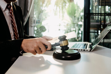 Justice and law concept.Male judge in a courtroom with the gavel, working with, computer and docking keyboard, eyeglasses, on table in morning light