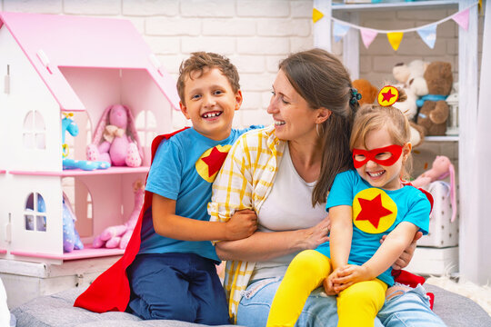 Happy family. A young woman plays with her children in superheroes.