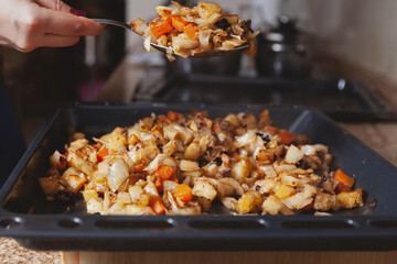 Large spoon with stewed vegetables over baking sheet