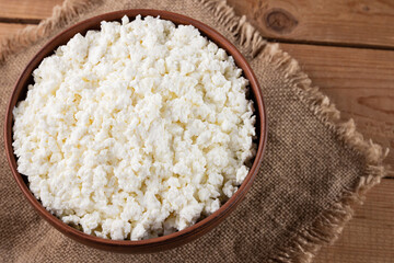 Cottage cheese on a burlap. Fresh cottage cheese in a bowl. Soft cheese on a wooden boards. Top view. Copy space