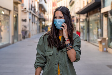 Fototapeta premium Woman wearing a protective mask on her face while using mobile phone in the street