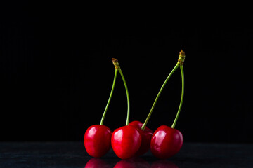 Red cherries on a black background. Two paired sweet cherries. Ripe juicy cherries. only cherries on a black background