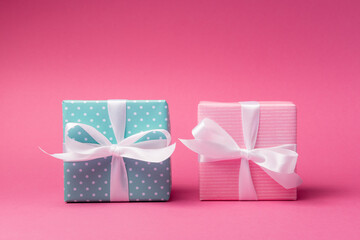 Pink and blue gift boxes with white bows over rose background