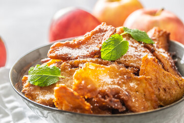 Finely fried apple pancakes sprinkled with vanilla sugar and cinnamon topped with mint leaves