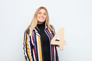 young pretty blonde woman excited, happy, joyful, holding a number 4.