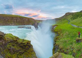 Amazing summer sunrise on Gullfoss Waterfall.
A man enjoys a view of a waterfall standing on a cliff. Colorful morning scene of Iceland. Midnight sun of Iceland. Visit Iceland. Beauty world.