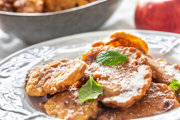 Finely fried apple pancakes sprinkled with vanilla sugar and cinnamon topped with mint leaves