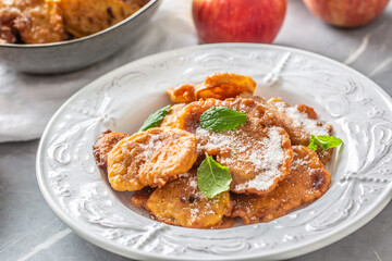 Finely fried apple pancakes sprinkled with vanilla sugar and cinnamon topped with mint leaves