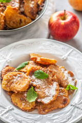 Finely fried apple pancakes sprinkled with vanilla sugar and cinnamon topped with mint leaves