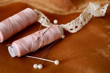 Two coils of threads on brown fabric close-up with a copy space