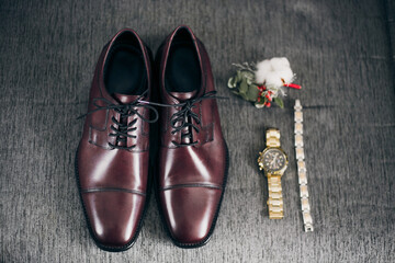 Top view on men's accessories: polished shoes, belt, boutonniere, watch. Groom fees on a wedding morning