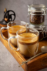 Dalgona coffee - the Korean coffee drink on wooden background. Instant coffee or espresso powder whipped with sugar and hot water. Iced whipped dalgona coffee concept.