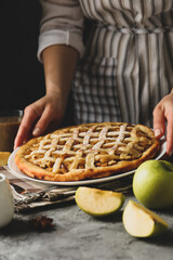 Housewife hold tasty apple pie on gray table. Homemade food