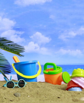 Summer vacations. Plastic toys for kids activities on a sandy beach. Blur sea background