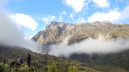 mountain landscape in the morning, two trekkers watching sunrise in Rwenzori Mountains in Uganda, Central Eastern Africa, outdoors travel concept, active lifestyle