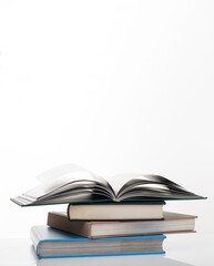 Education concept. Stack of closed books and the one on the top open isolated on white background. Vertical photo, copy space.