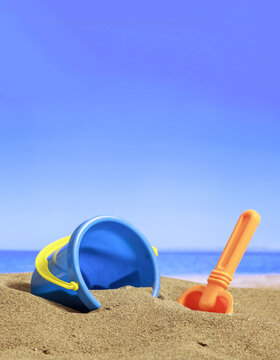 Summer vacations. Bucket with accessories on a sandy beach. Blur sea background.