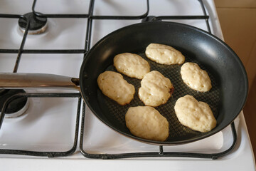 Yeast pancakes on a frying pan. Frying pan on a white gas stove in the kitchen in Ukraine. The evening sun illuminates the kitchen. 