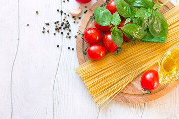 Ingredients for traditional Italian pasta spaghetti, tomatoes, basil and olive oil top view copy space.