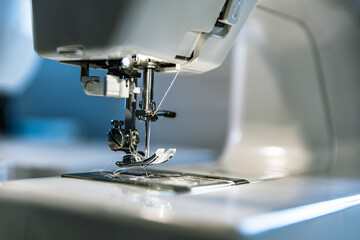 Close up of presser foot in sewing machine with needle and thread. Concept of sewing hobby and dressmaking industry 