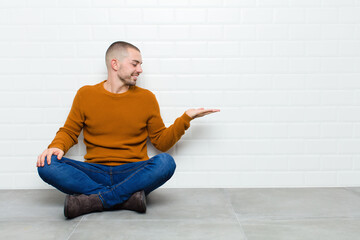 young handsome man feeling happy and smiling casually, looking to an object or concept held on the...