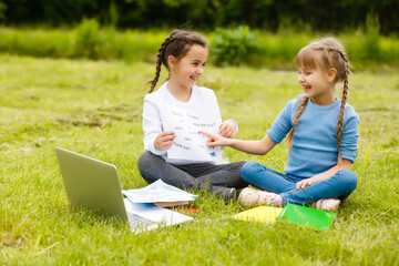 Fototapeta premium Pretty stylish schoolgirls studying online lesson in the courtyard, social distance during quarantine, self-isolation, online education concept