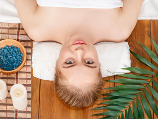 Obraz na płótnie Canvas Wellness center. Girl lies on massage table, beside salt and spa accessories