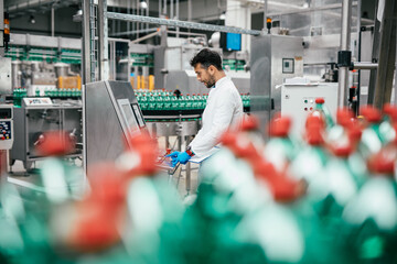 Male worker in bottling factory checking water ottles before shipment. Inspection quality control.