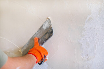 Stucco wall builder. Men's hands plaster the wall. Spatula in the hands of a male stator. Construction work in the house, painting