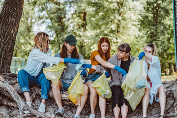 Group of activists friends collecting plastic waste at the park. Environmental conservation.