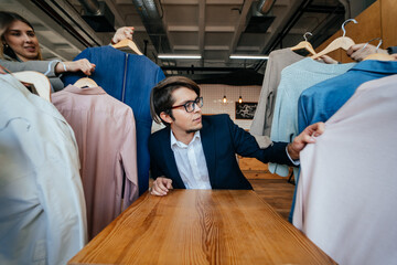 Young stylist looking through set of shirts for fashion shooting