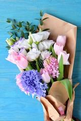 Trendy bouquet of flowers with pink tulips, elegant hyacinths and tender eustoma on blue wooden background. Romantic gift. Spring flowers. 
