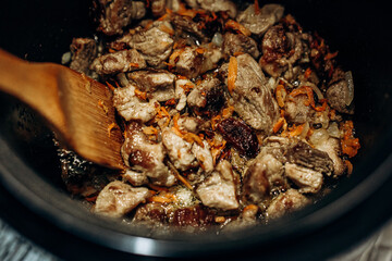 Onions with carrots are fried. Home cooking. Pilaf with meat