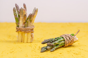 Green and white fresh asparagus on a yellow background