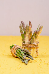 Green and white fresh asparagus on a yellow background
