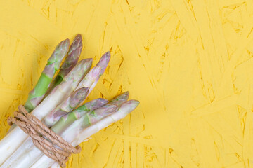 Green and white fresh asparagus on a yellow background