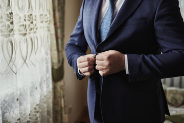 Businessman wears a jacket, male hands closeup,groom getting ready in the morning before wedding ceremony