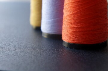 Colorful sewing threads on black background. Sewing concept. Selective focus.

