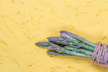 Green and white fresh asparagus on a yellow background