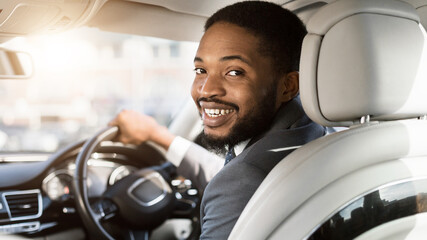 Cheerful Black Man Driving Automobile Sitting In Driver's Seat, Panorama